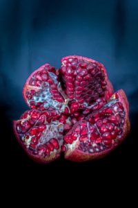 Red pomegranate, cut open to show the seeds, on a dark blue background