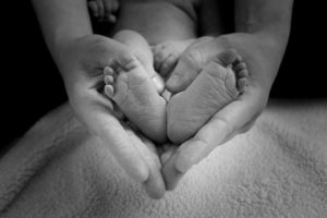 Adult hands holding baby feet, forming the shape of a heart