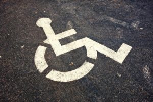 Black asphalt parking lot surface with white pictogram of person in wheelchair