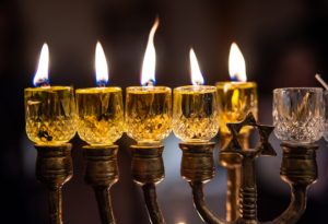 Five glass oil lamps with flames, as part of a Hanukkah menorah