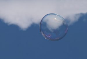 Blue sky, white cloud with a giant soap bubble appearing to magnify some of the cloud.