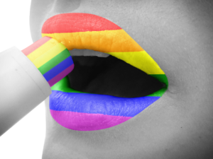 Person with white skin and rainbow lips, using a rainbow lipstick