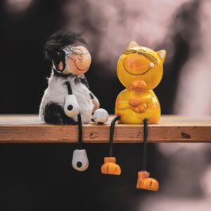 A toy cow and a toy cat sitting together on a shelf