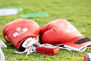 Two red boxing gloves and folded red wraps on a green field background