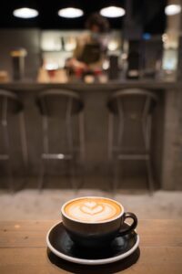 Blurred cafe background, wooden table in the foreground, with a cup of coffee with beautiful foam art