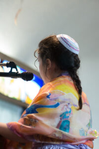 12 y/o Shira with the scene of the brothers embracing on the back of her tallit.